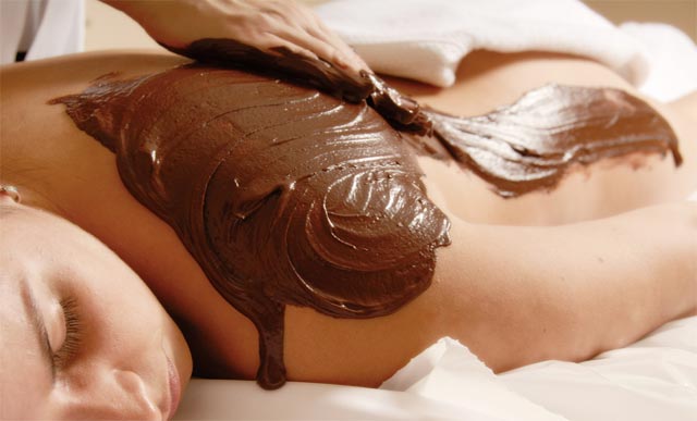 chocolate being spread over a female body while being massaged